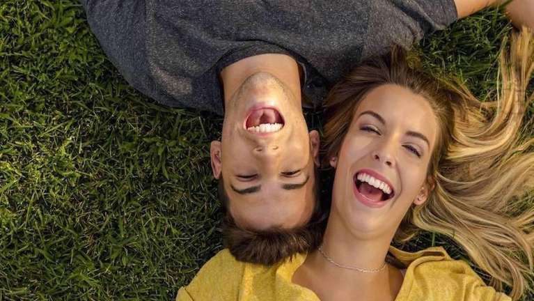 couple laying down on grass smiling